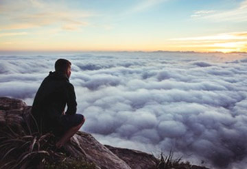 man sitting above mountain edge 
