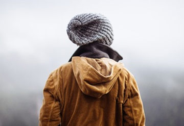 back photo of a man wearing cap and coat